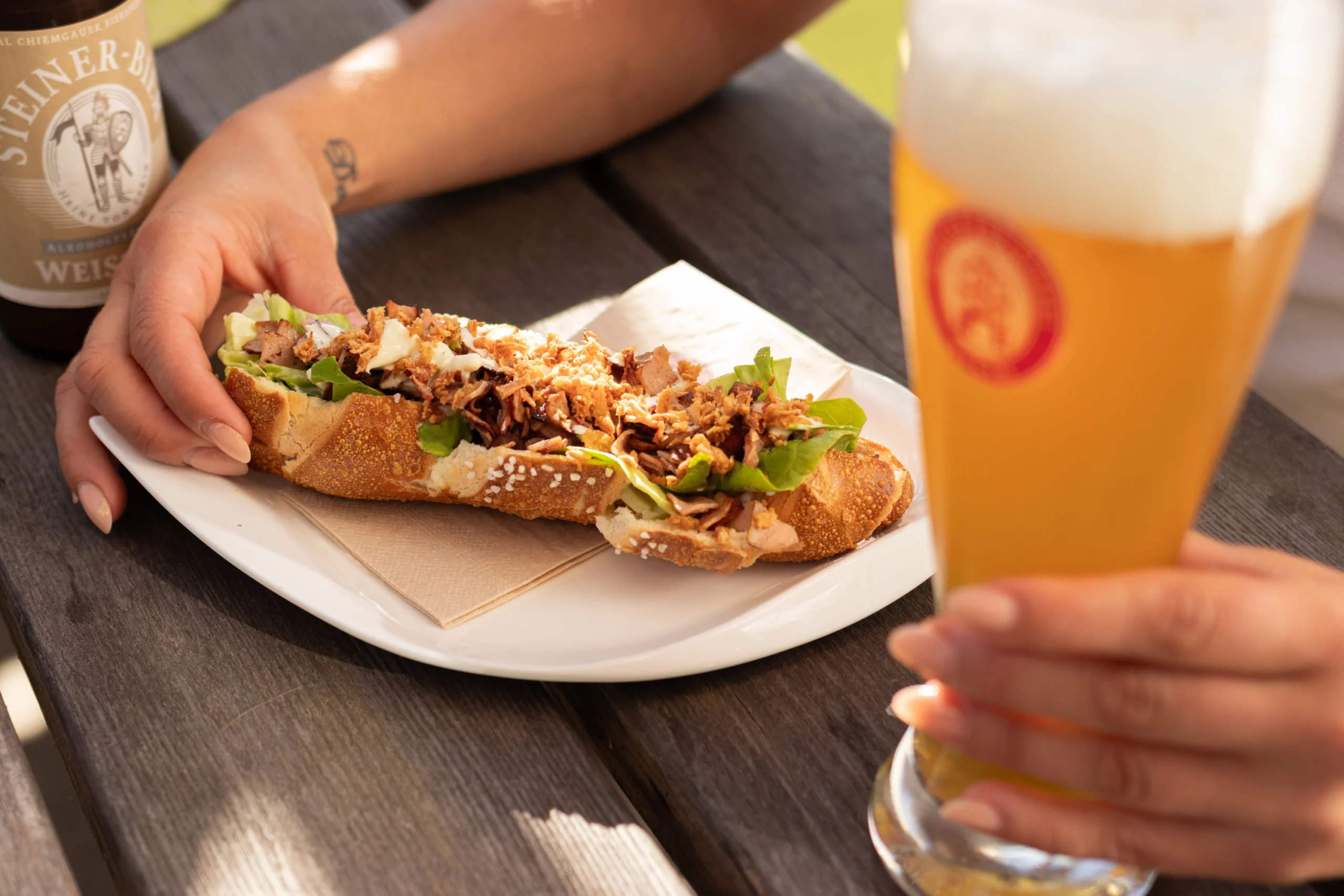 Herzhaft belegte Laugenstange und alkoholfreies Weißbier im Glas